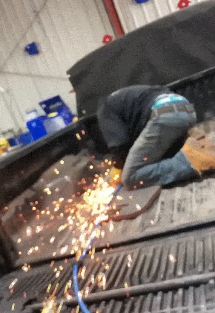 A Full Tilt technician grinding metal in the shop, sparks flying