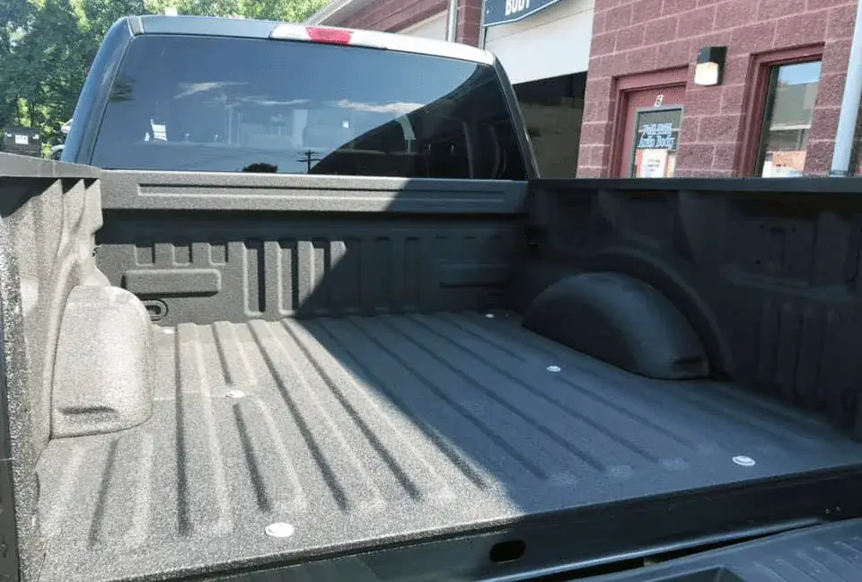A spray-on bed liner being applied to a pickup truck bed at the Full Tilt shop